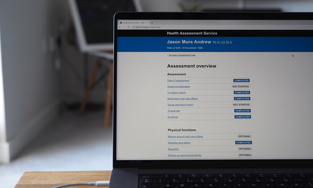 A laptop sits open with the Health Assessment Service on the screen.